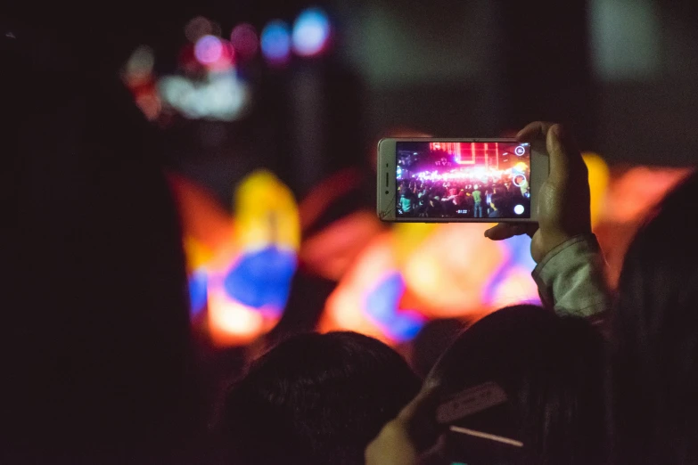 the lights are shining brightly and people are holding up their phones