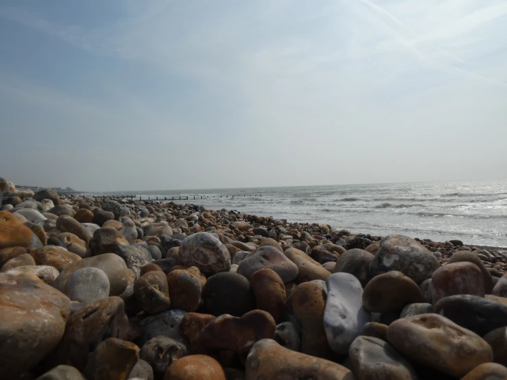 a bunch of rocks on the beach near water