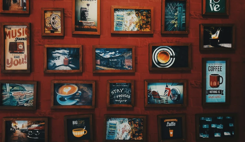 the red wall has many coffee posters on it