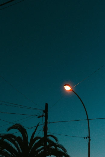 a single street lamp in front of some power lines