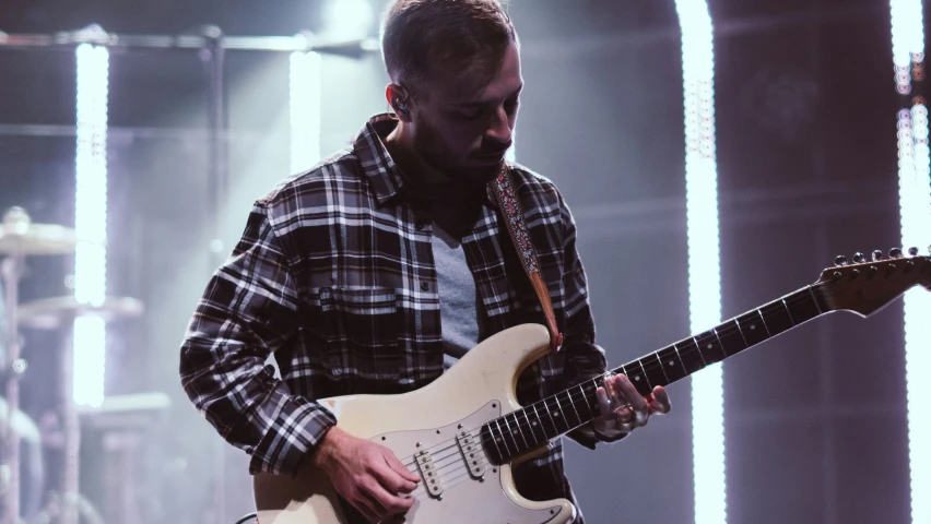 a man in plaid shirt holding a guitar