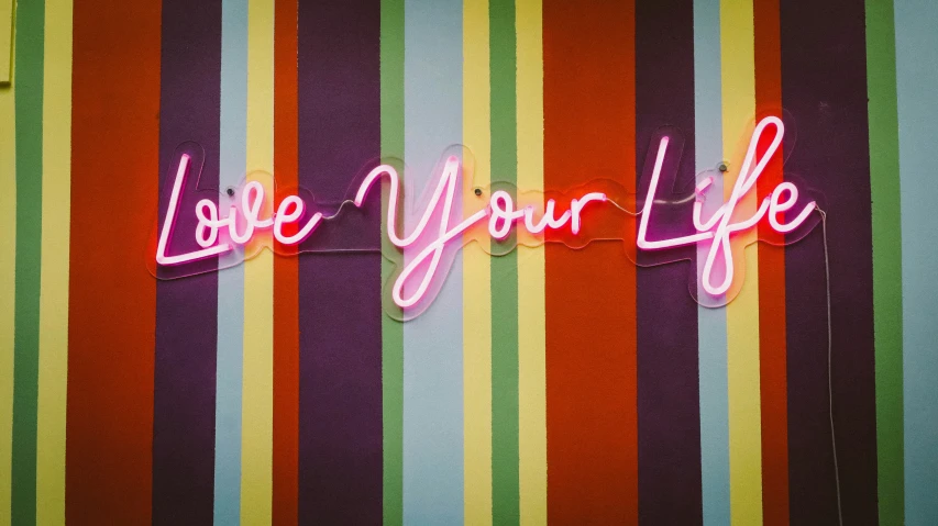 neon sign that says love your life hanging off a wall