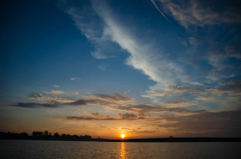 the sun setting over the water of a lake