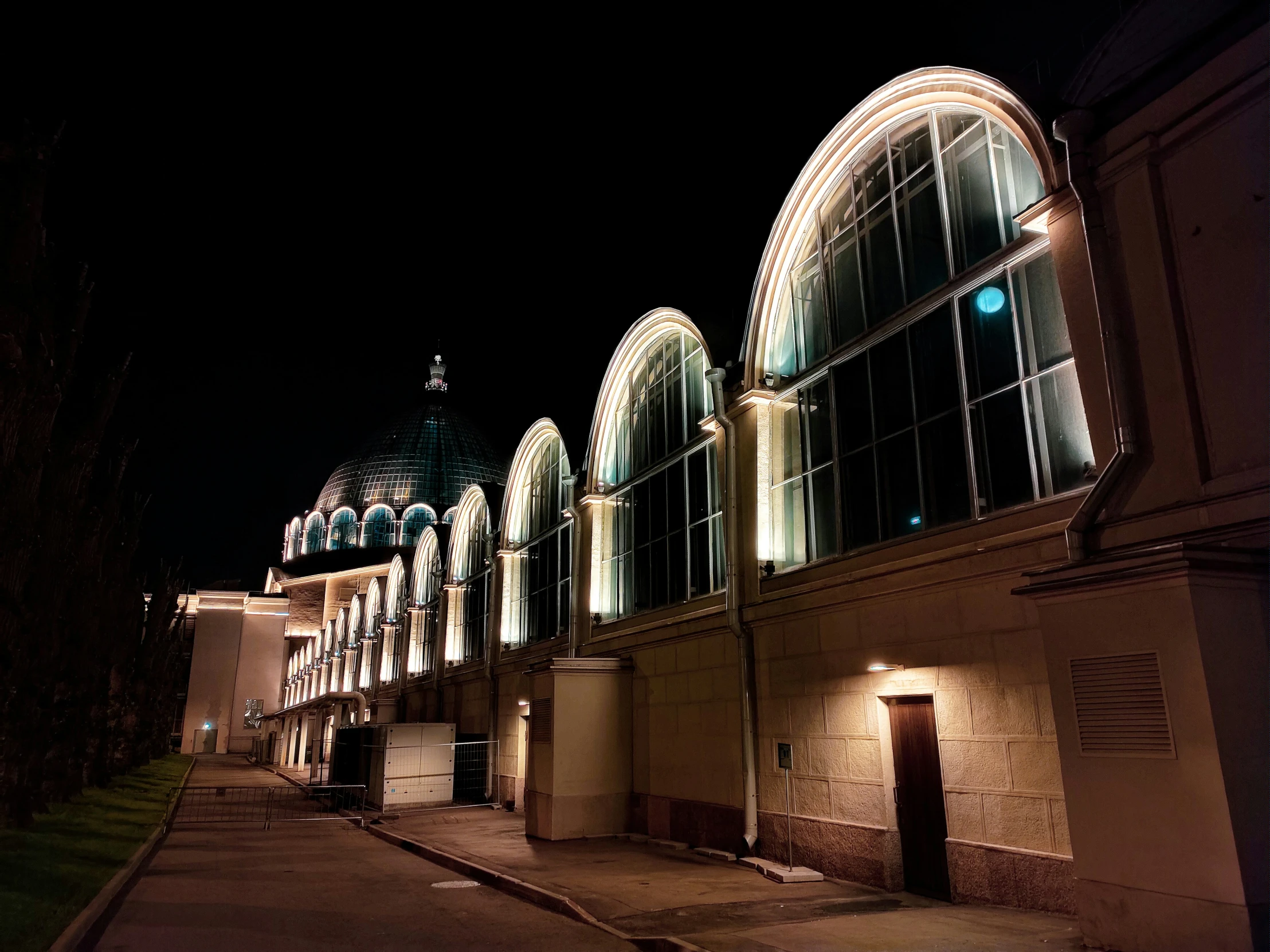 a night scene in a city with buildings and an archway