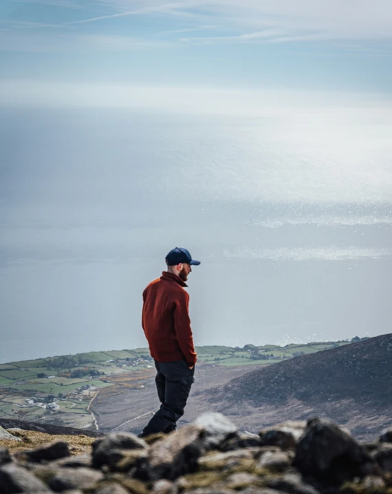 a man looking off into the distance while standing on a rocky ledge