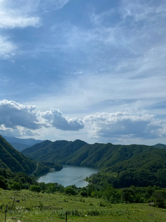 a grassy hill and pond surrounded by a beautiful view