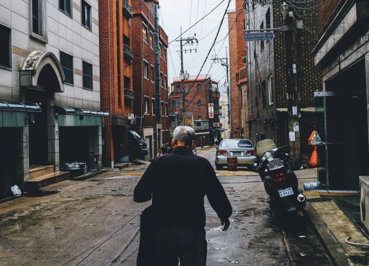 an old man is walking down the street of a city