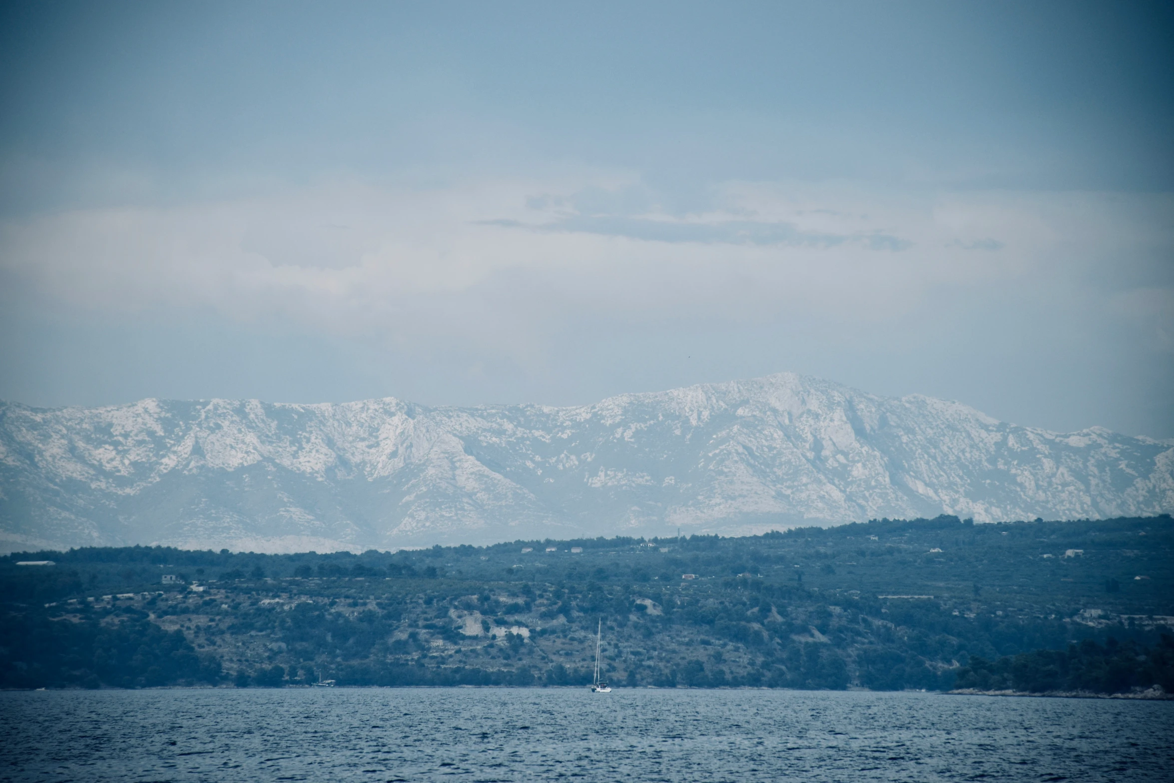 an empty boat traveling across a body of water with mountains in the background