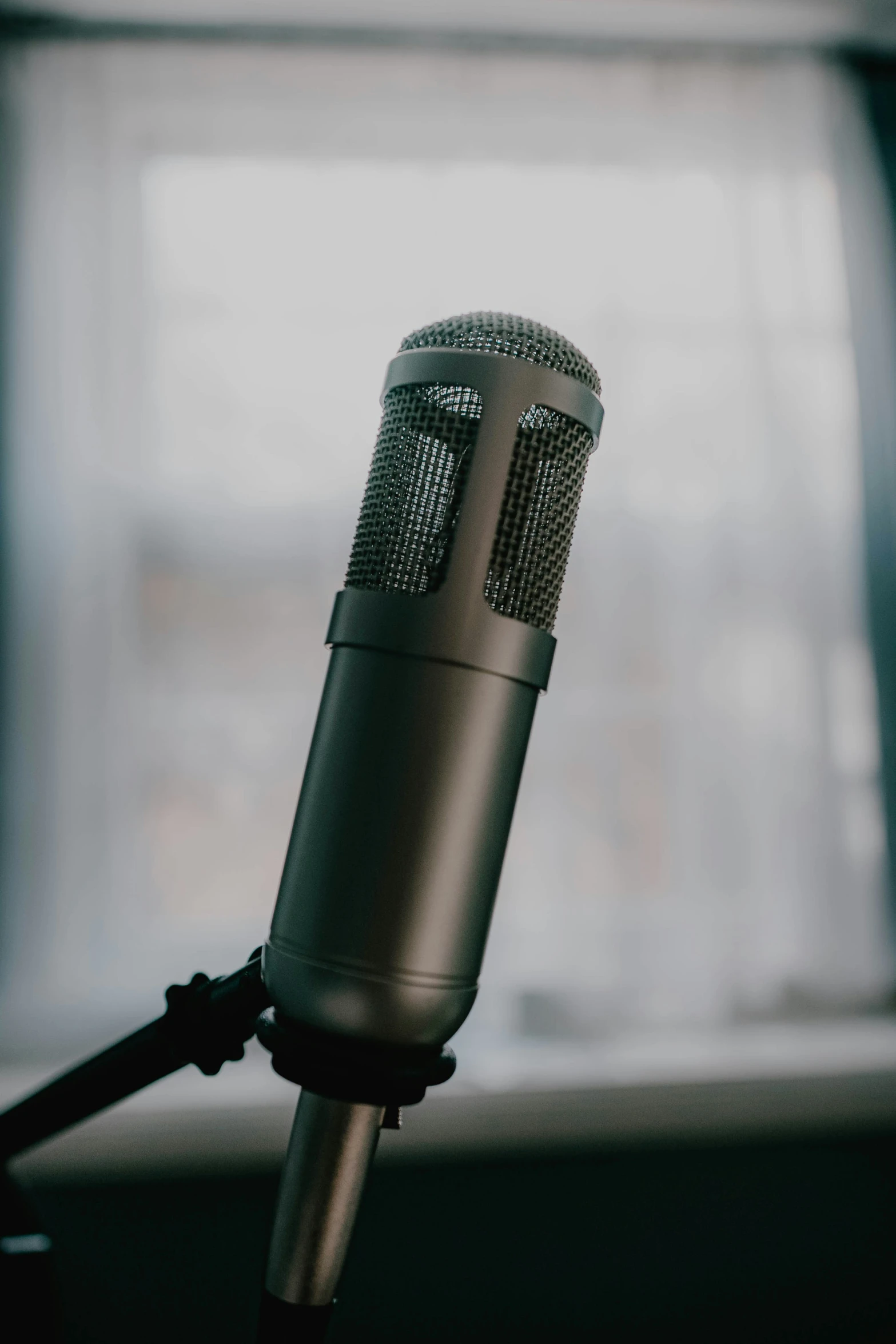 a microphone with an open mic section on a desk in front of a window