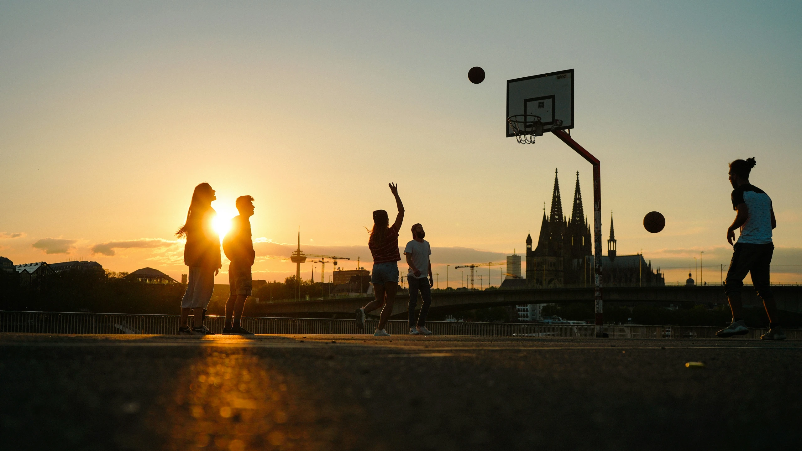 people play basketball at sunset on the side walk