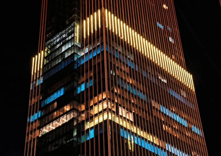 a very tall glass building with different colored lights