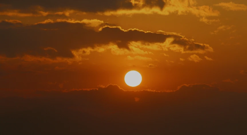 the sun is setting as it shines in front of clouds