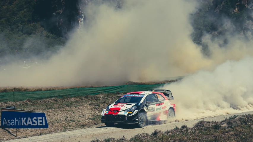 a red and white car is driving down a dirt road