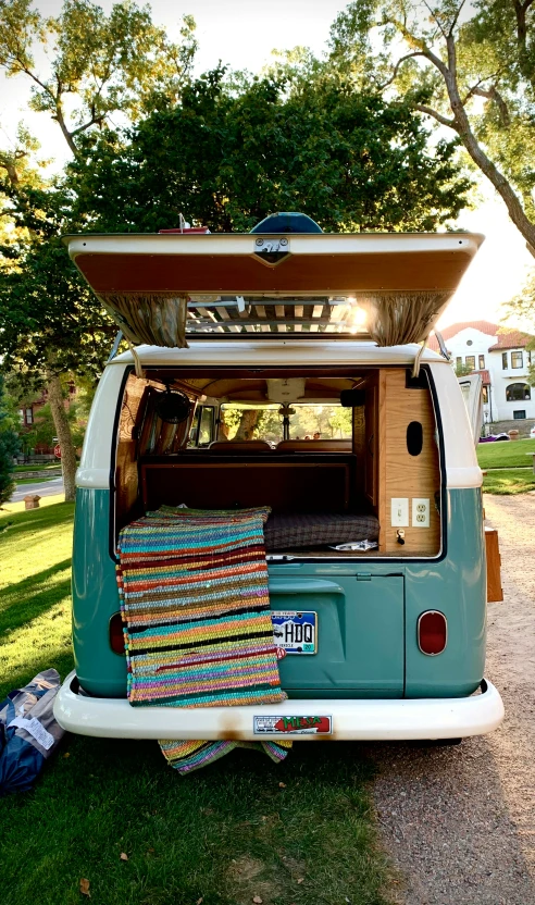 a camper van parked near the grass with it's doors open