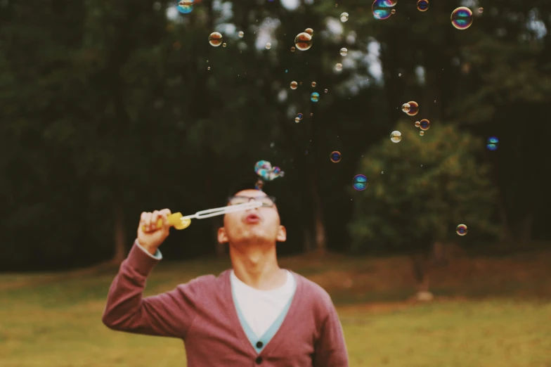 a man blowing bubbles from a stick in a park