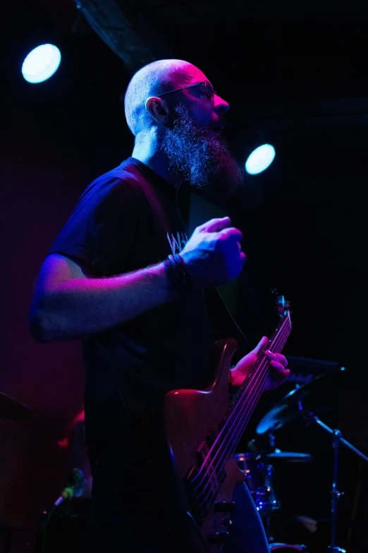 a man in a black shirt holding his bass while standing on stage