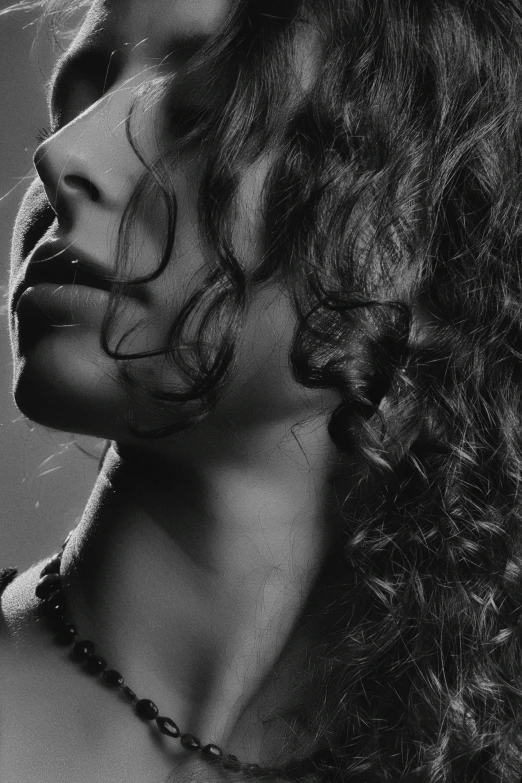 a woman with dark curly hair wearing a necklace