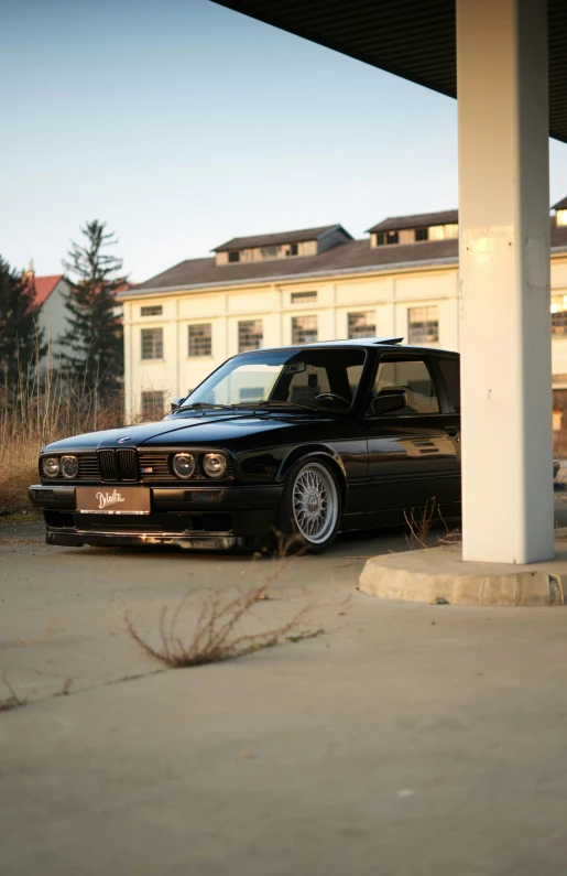 a black sedan is parked under a white pillar