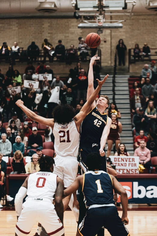 two basketball players reach for the ball in the middle of their game