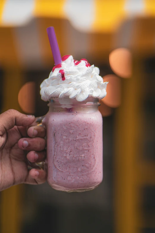 a person holding up a pink drink on top of a table