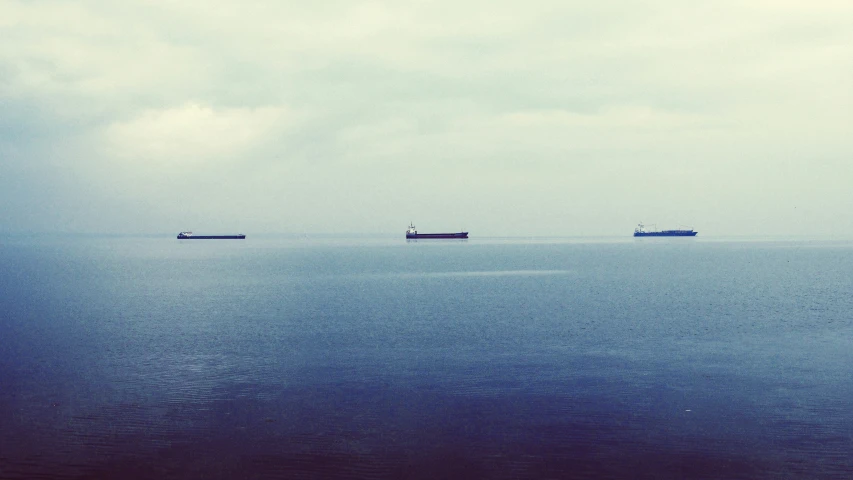 four cargo ships are shown anchored on the water