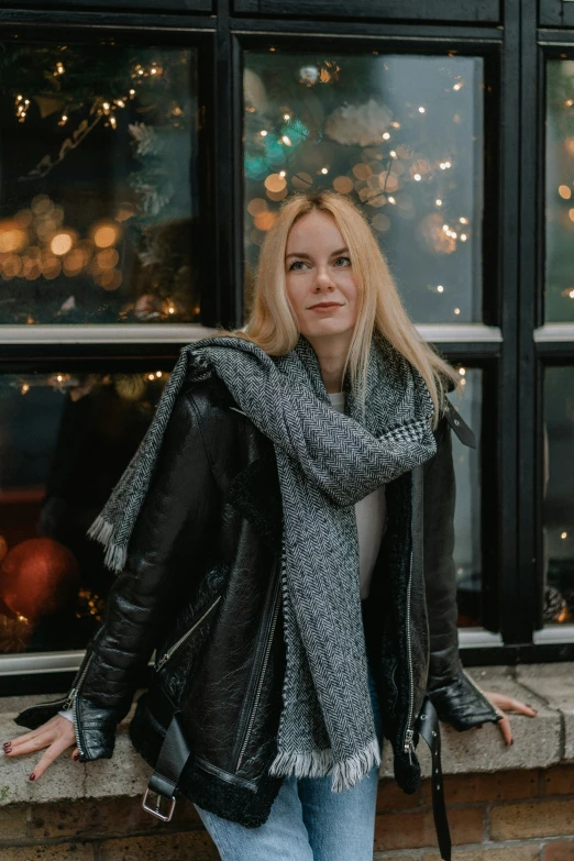 a woman is standing by the window wearing her scarf