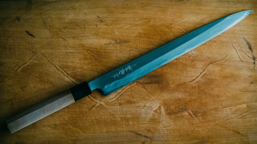 a blue knife laying on top of a wooden table