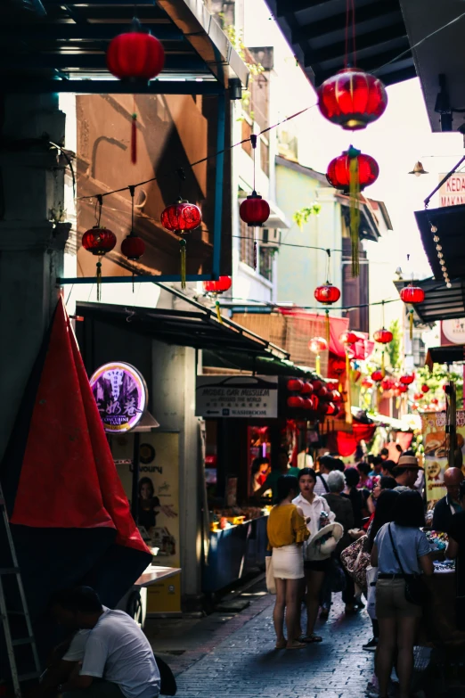 people stand on the side of a street with lanterns in the sky