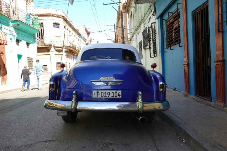 an old blue car is parked on the street