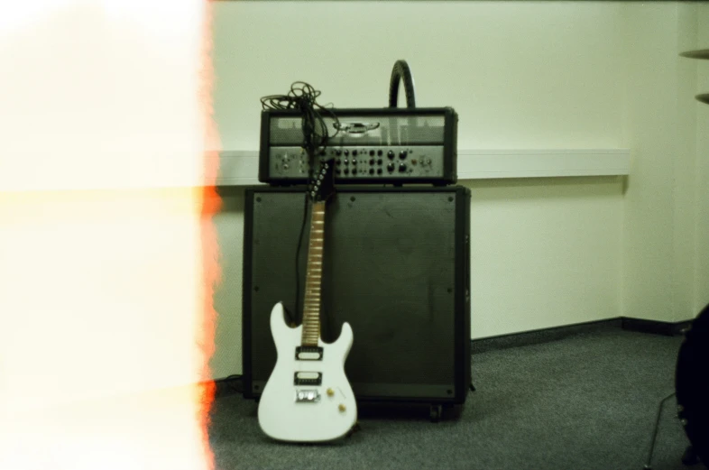 a guitar sitting in front of a amp in a corner