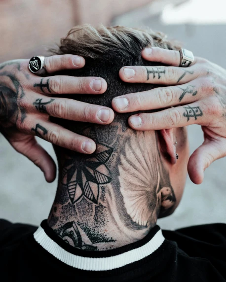 tattooed hands covering the top of a person's head
