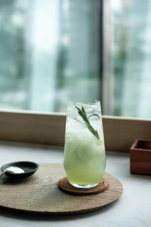 a drink glass with green liquid sitting on top of a coaster