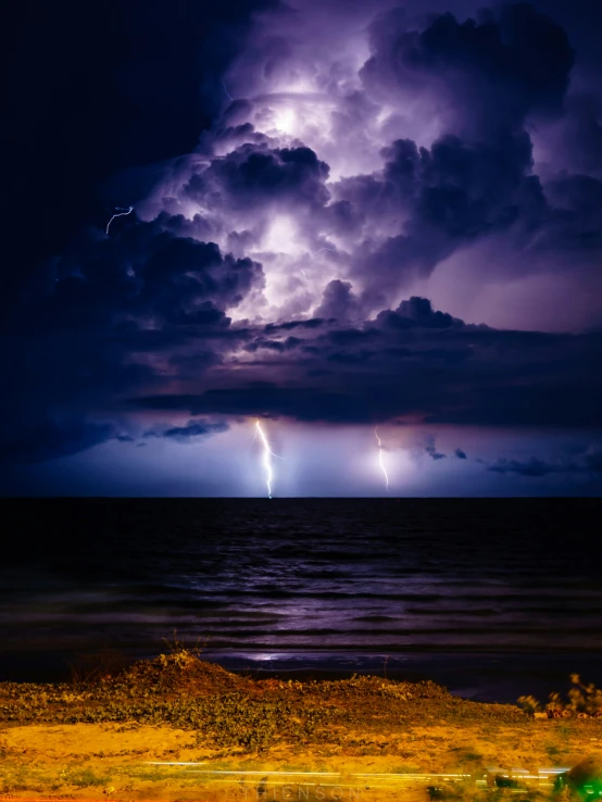 lightning is coming through the clouds over the ocean