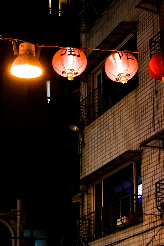 red lanterns are strung between the windows of an apartment building