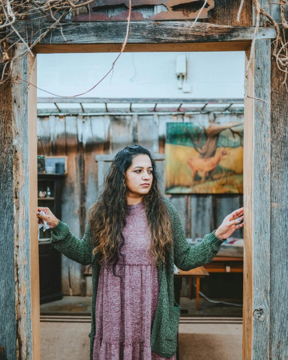 a young woman holding her hand up in an old doorway