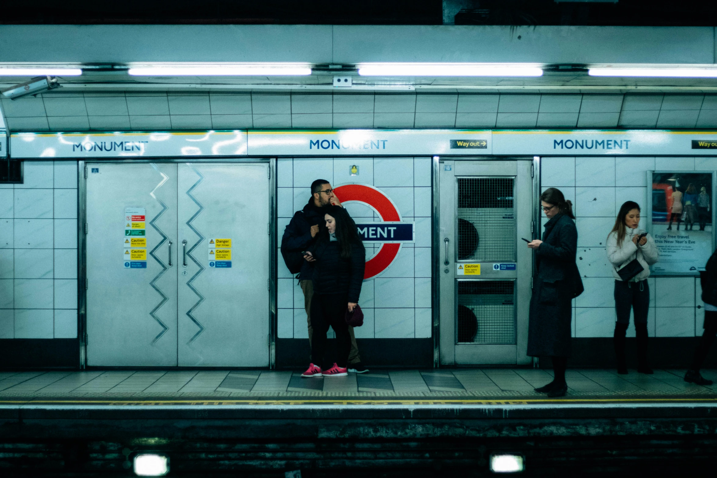 people standing in front of a subway station with one on the phone