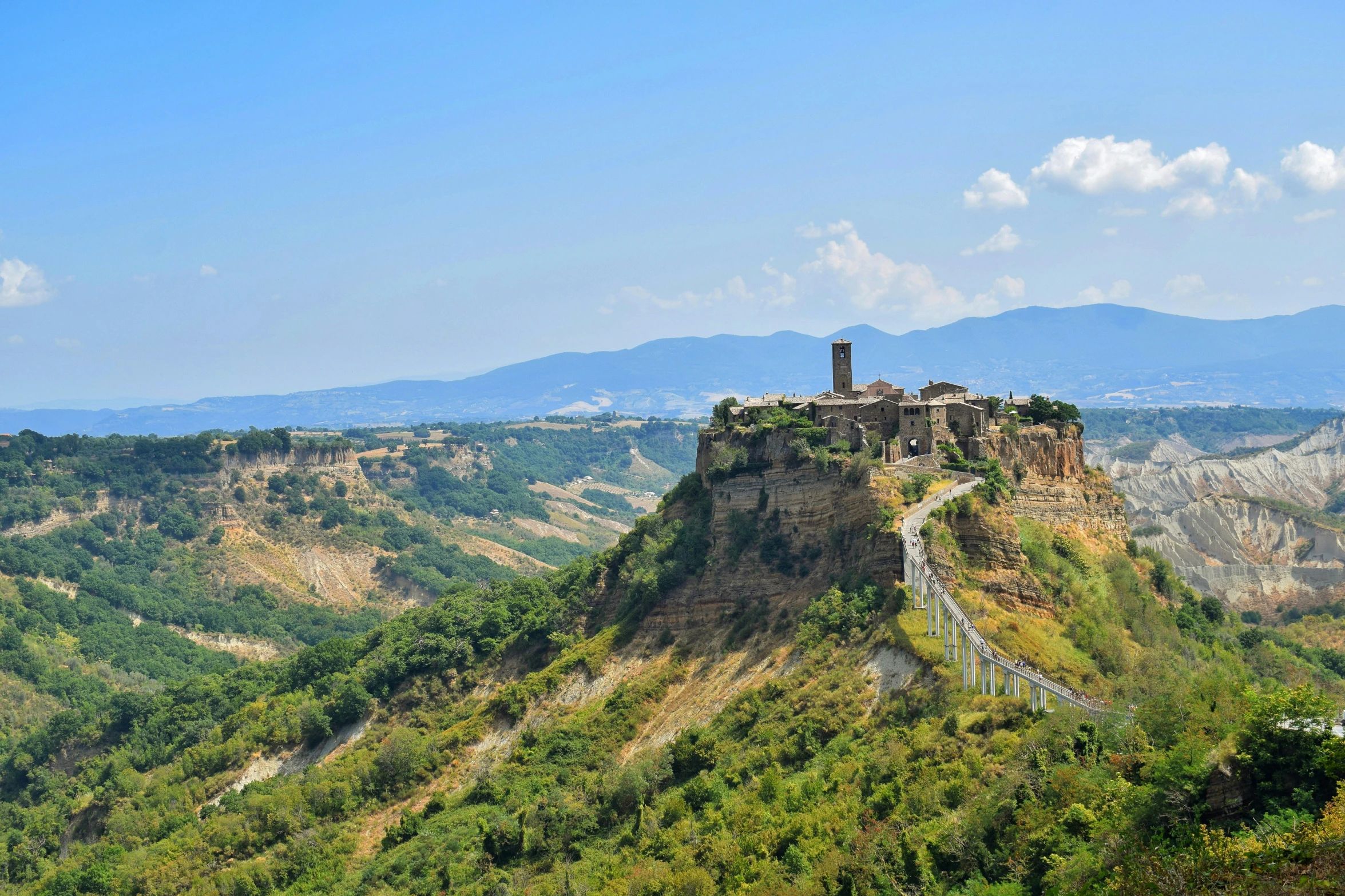 a stone castle in a green valley with mountains in the background