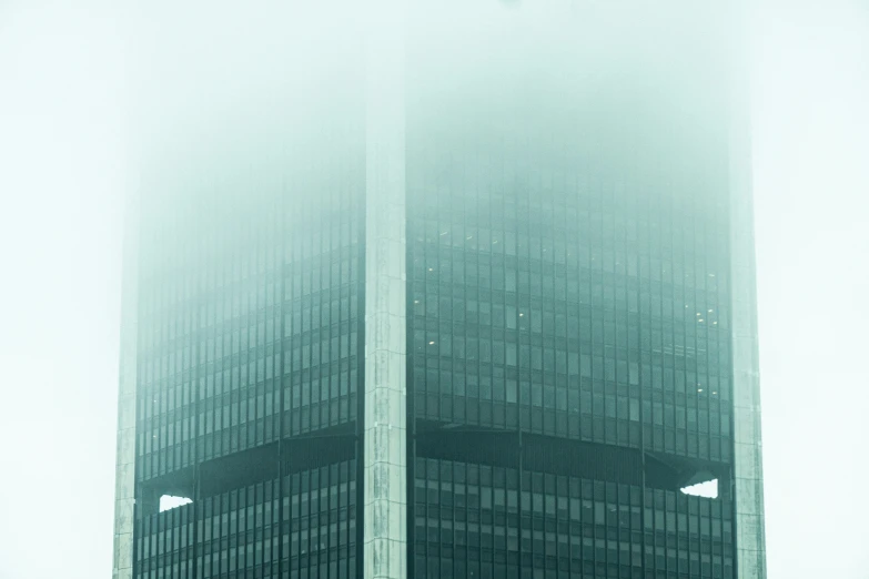 two tall buildings standing in the fog with lights