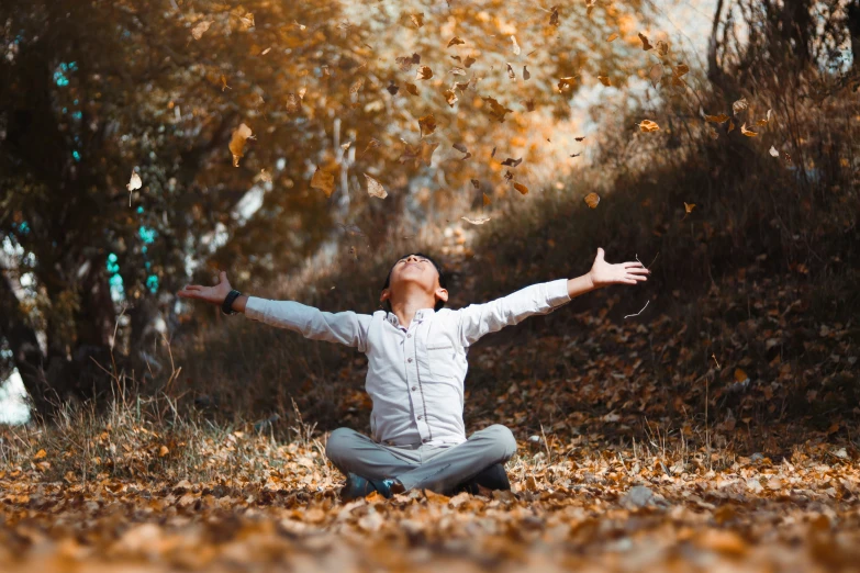 a young man is sitting outside in the grass