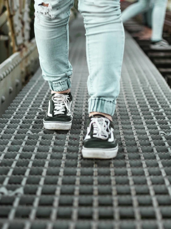 person wearing sneakers walking on platform of industrial walkway