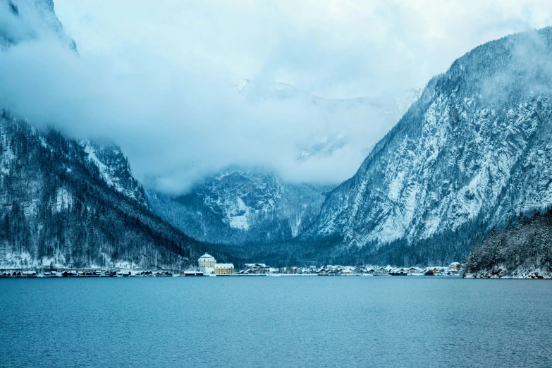 snow - covered mountains and trees surrounding the water near town