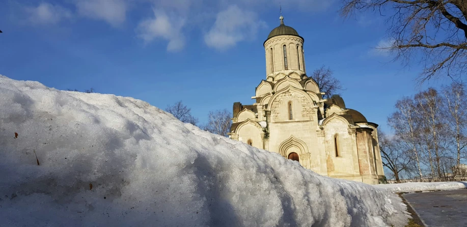 a church with a clock tower is behind a wall of snow