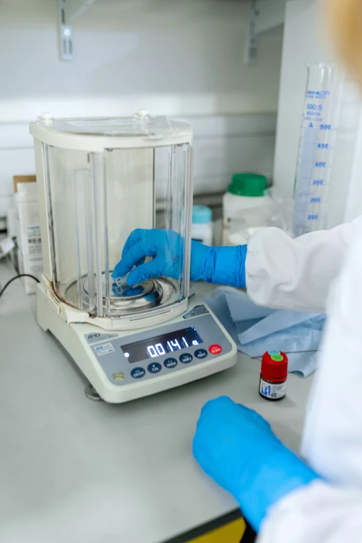 a scientist in protective gloves examines a container of fluid