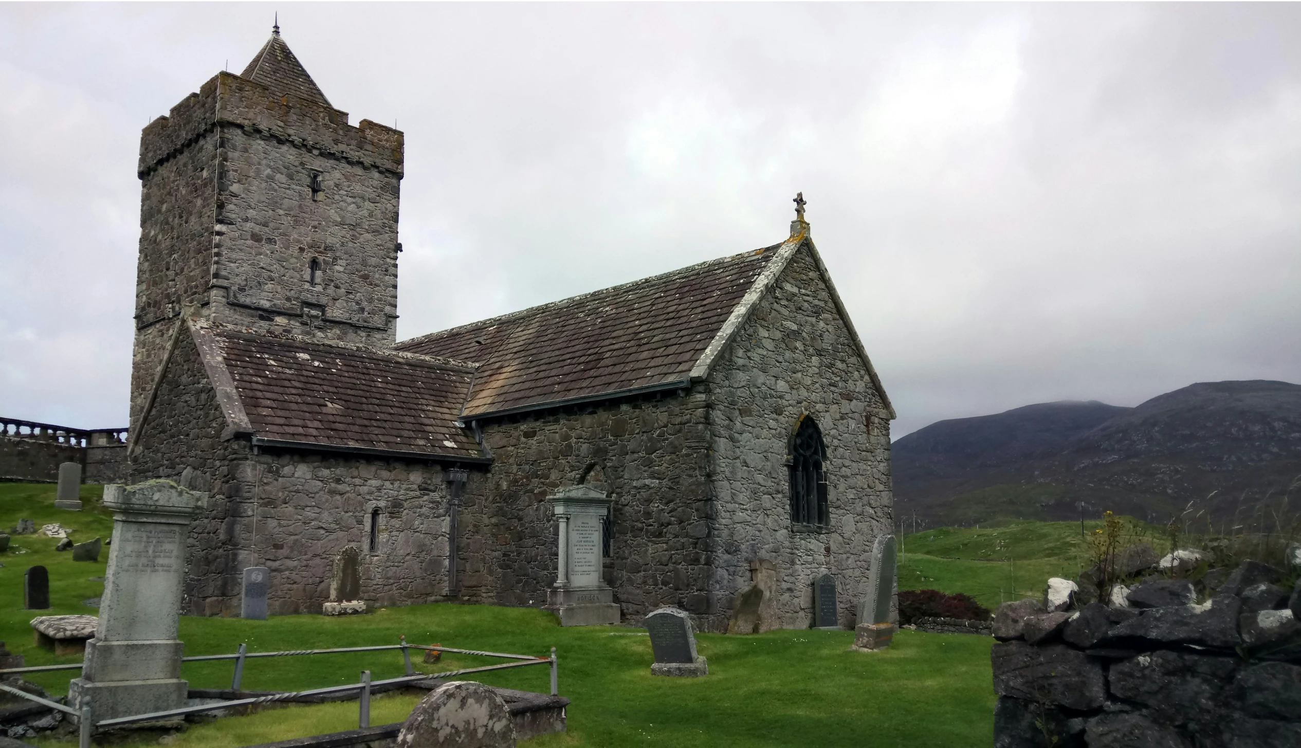 an old church on the hillside with a cemetery nearby