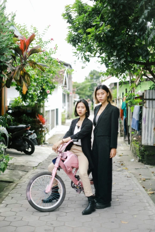 a couple of women standing next to a pink bicycle