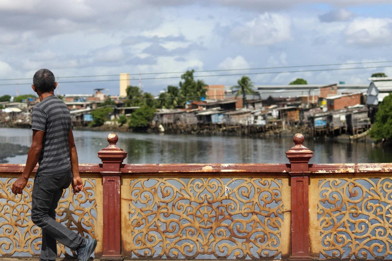 a man walking across a bridge looking over a river