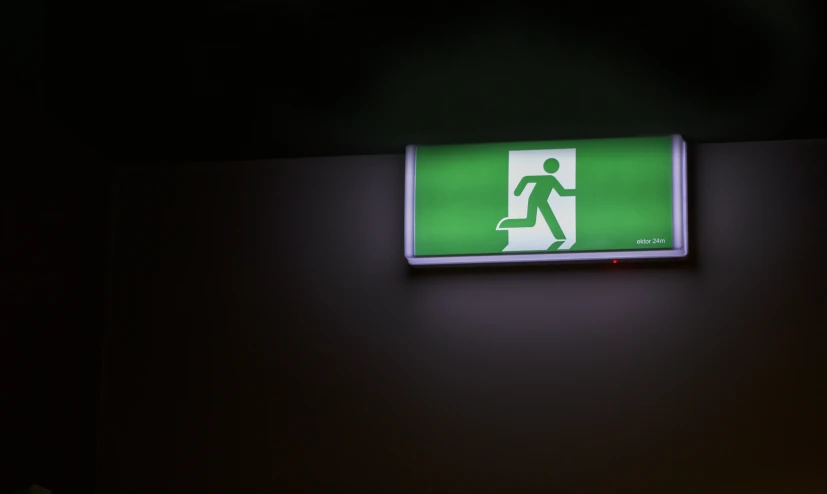 a green exit sign is hanging above a doorway
