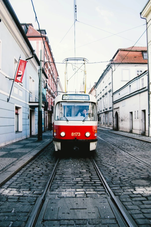 a small red and white train on tracks next to a building