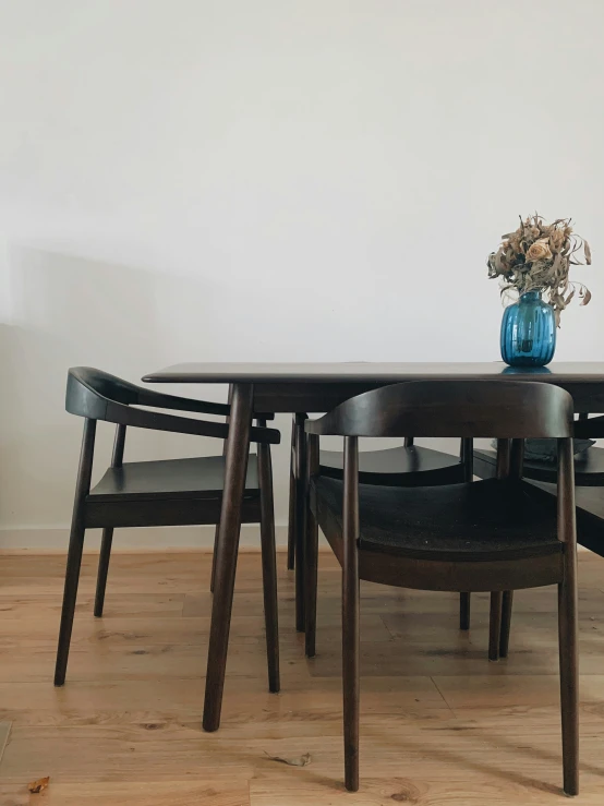 a table is surrounded by black chairs and a vase filled with flowers