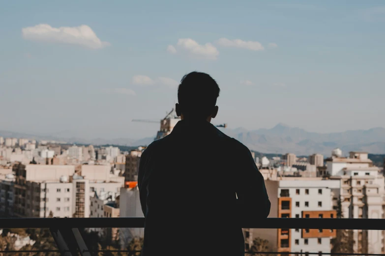 a man is standing at a balcony looking out at the city